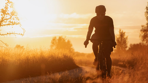 Fahrradfahrer fährt bei Sonnenuntergang einen Waldweg entlang