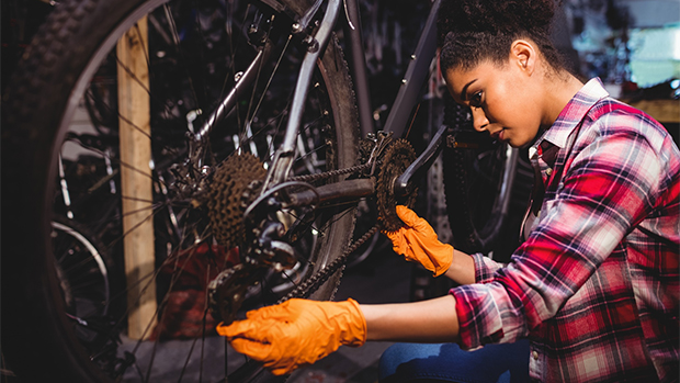 Eine Frau mit Handschuhen schraubt am Fahrrad