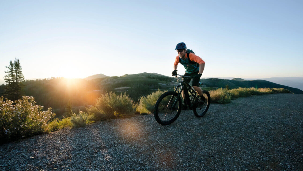 Ein Mann mit Helm fährt bei Sonnenuntergang mit dem Fahrrad.