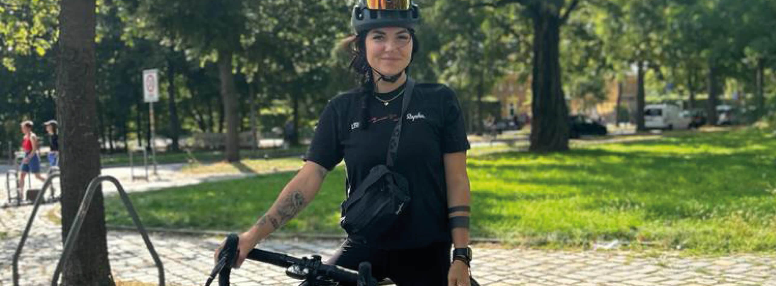 Eine sportliche Frau sitzt auf ihrem Cannondale-Bike in einem Park und lächelt in die Kamera. Es ist Natalie von den #LJBfemmes.