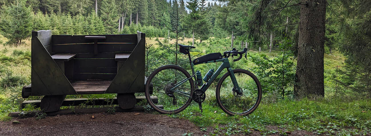 Ein Fahrrad von Cannondale steht neben einer Holzbank.