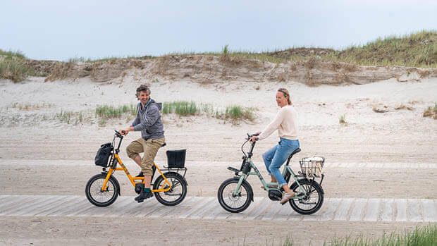 Ein Mann und eine Frau fahren mit I:SY-Rädern am Strand.
