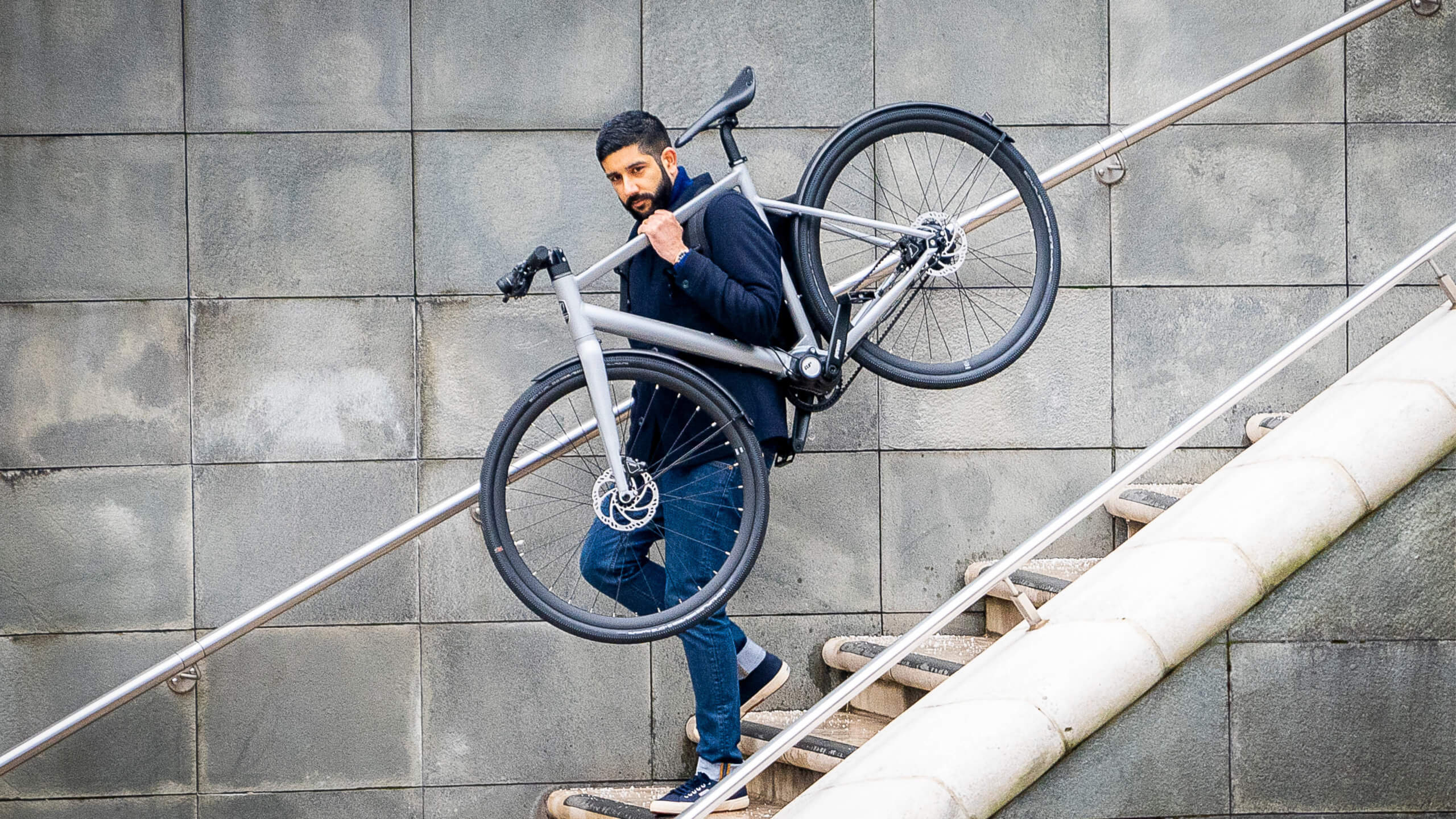 Ein Mann trägt ein Fahrrad die Treppe hinunter