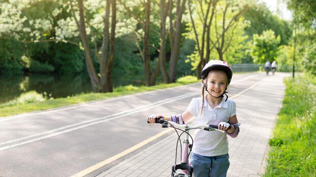 Lachendes Mädchen mit Helm und Fahrrad