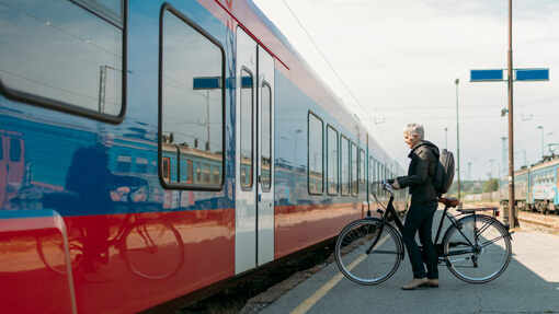 Eine ältere Frau steht mit einem Fahrrad vor einer Bahn