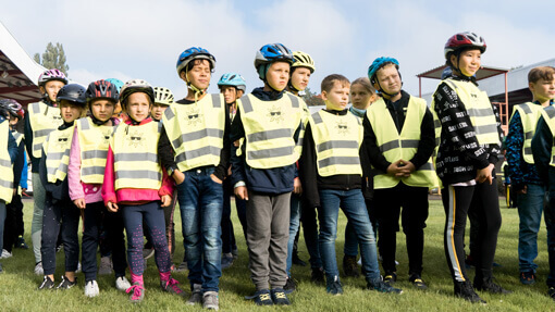 Eine Gruppe aus Kindern steht mit Fahrradhelmen und Warnwesten auf einer Wiese