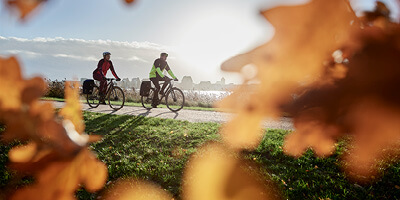 Zwei Radfahrer fahren im Herbst am See