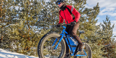 Mann fährt mit Mountainbike eingeschneiten Hügel hoch