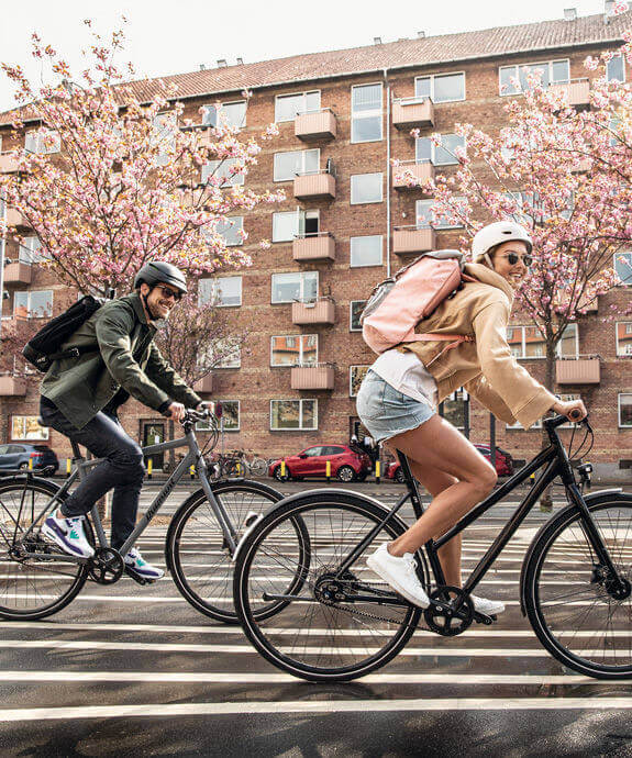 Zwei Fahrradfahrer fahren mit Rucksack auf ihren Rädern durch eine Stadt