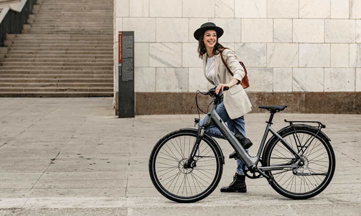 Frau mit schwarzem Hut fährt auf E-Bike von Tenways durch die Stadt
