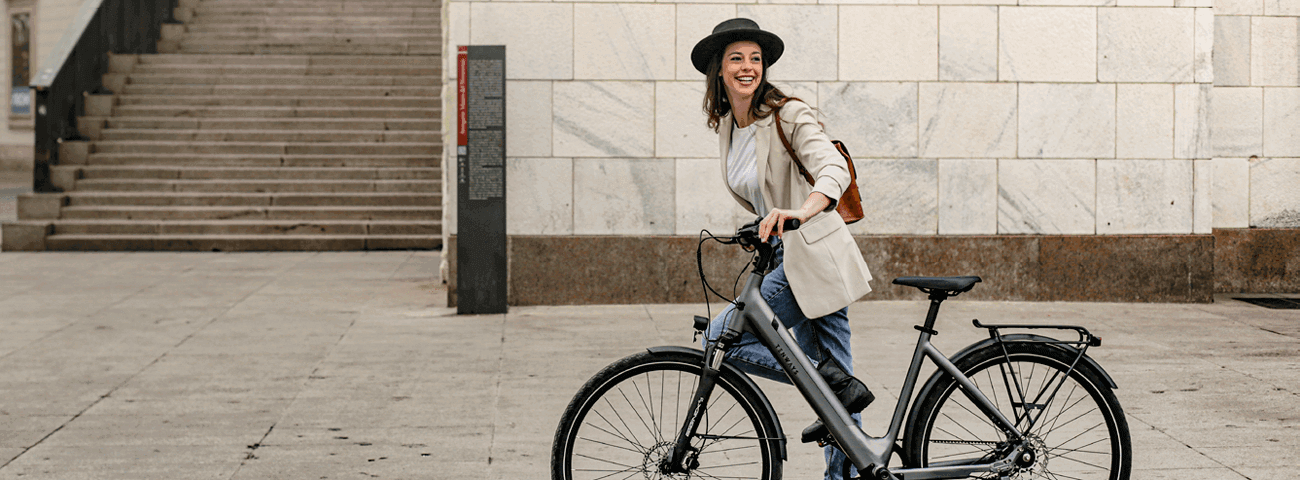 Frau mit schwarzem Hut fährt auf E-Bike von Tenways durch die Stadt