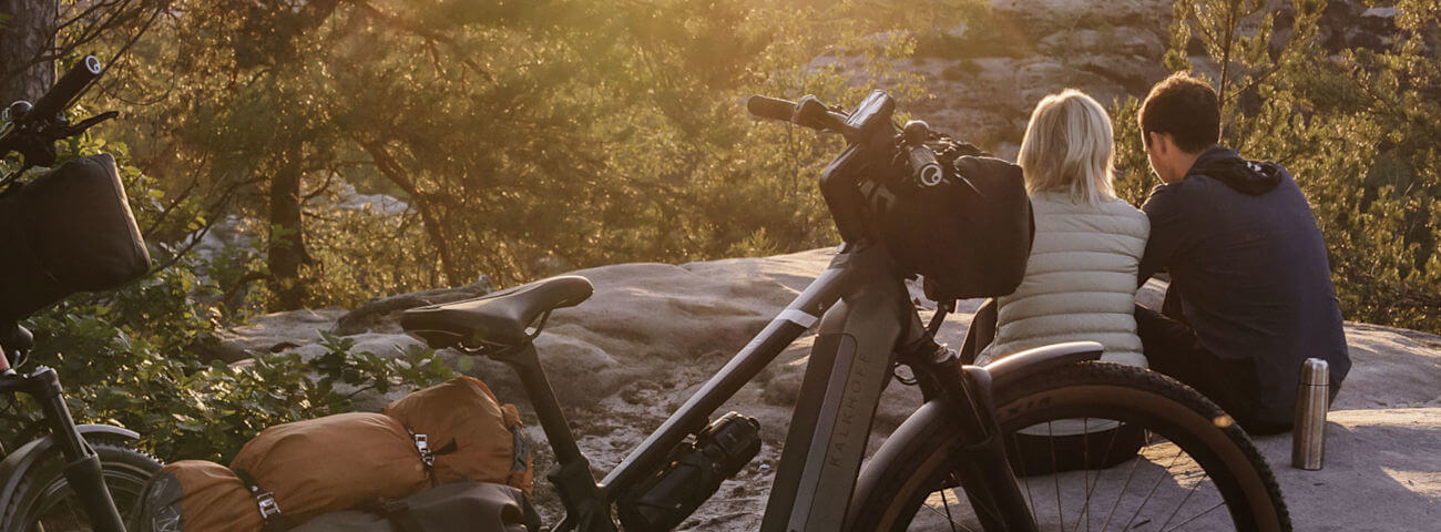 Zwei Radfahrer pausieren auf einem Felsen bei Sonnenuntergang