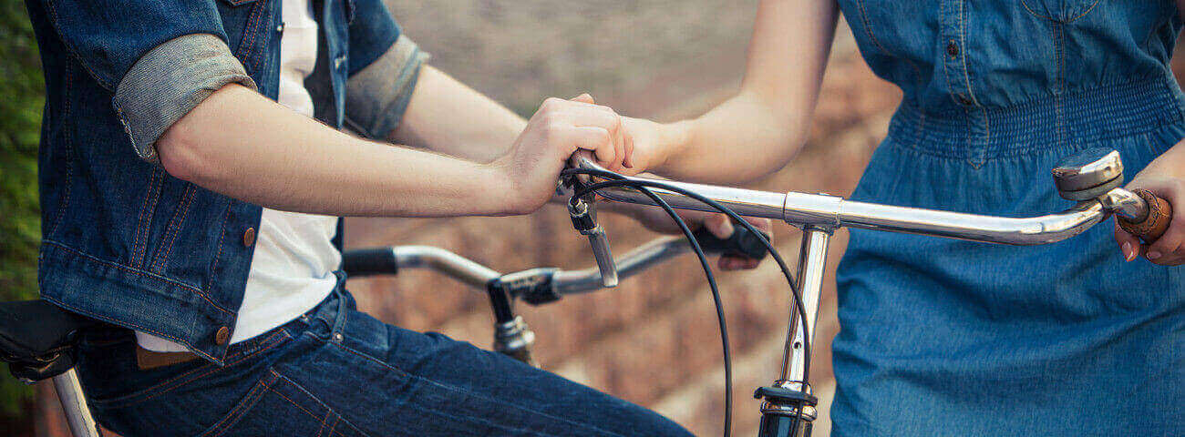 Eine Frau und ein Mann halten Händchen am Fahrradlenker