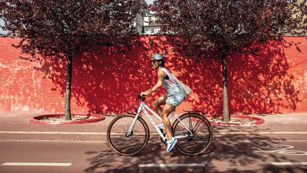 Eine Frau mit Fahrradhelm fährt an einer roten Mauer vorbei